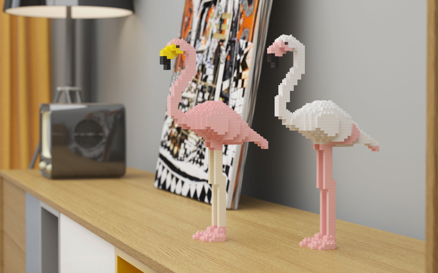 Two pink and white block-built flamingo figurines standing on a light wood console table in a modern room setting.