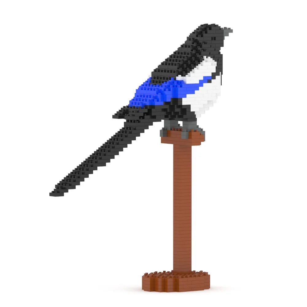 A small bird figurine built from interlocking blocks, perched on a brown stand against a plain white background. The bird is primarily black and white with a bright blue wing accent.