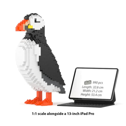 A 1:1 scale brick building set of a puffin, shown next to a 13-inch iPad Pro displaying product specifications. The puffin is constructed with white, black, and orange building blocks, and the text at the bottom reads '1:1 scale alongside a 13-inch iPad Pro'.