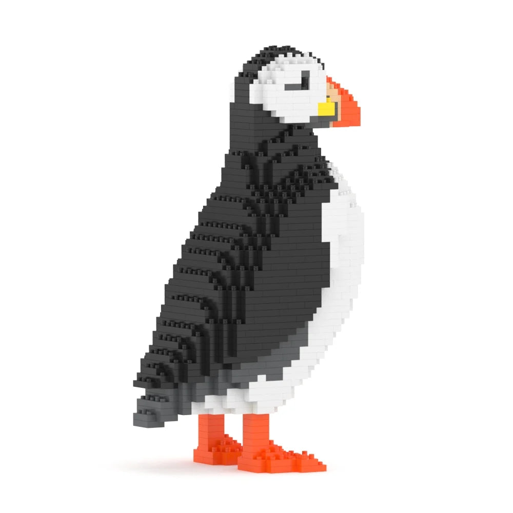 A pixelated puffin bird figure built from small interlocking blocks, shown in side profile on a plain white background. The bird is primarily black and white with bright orange feet and beak accents and a small yellow accent near the beak.