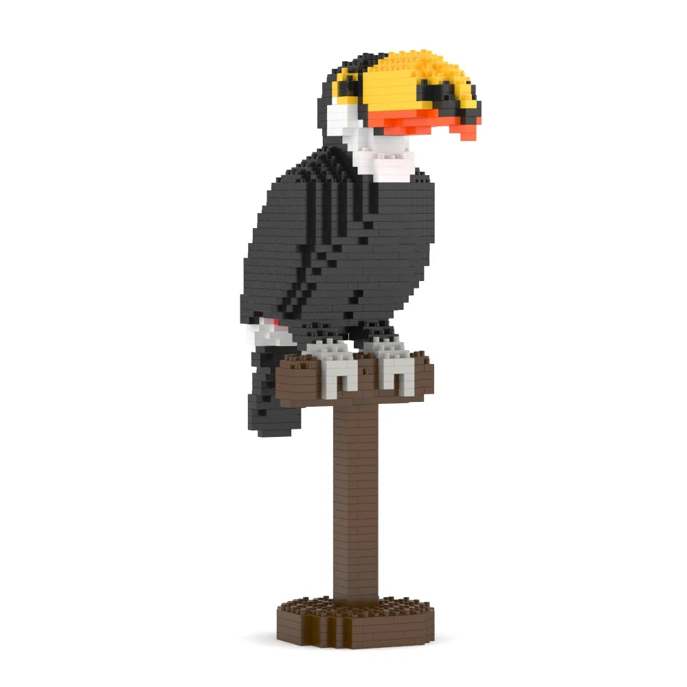 A pixelated toucan bird sculpture perched on a brown post, built from small block-like pieces. The bird has a black body, white face, and a yellow beak with orange accents, shown on a plain white background.