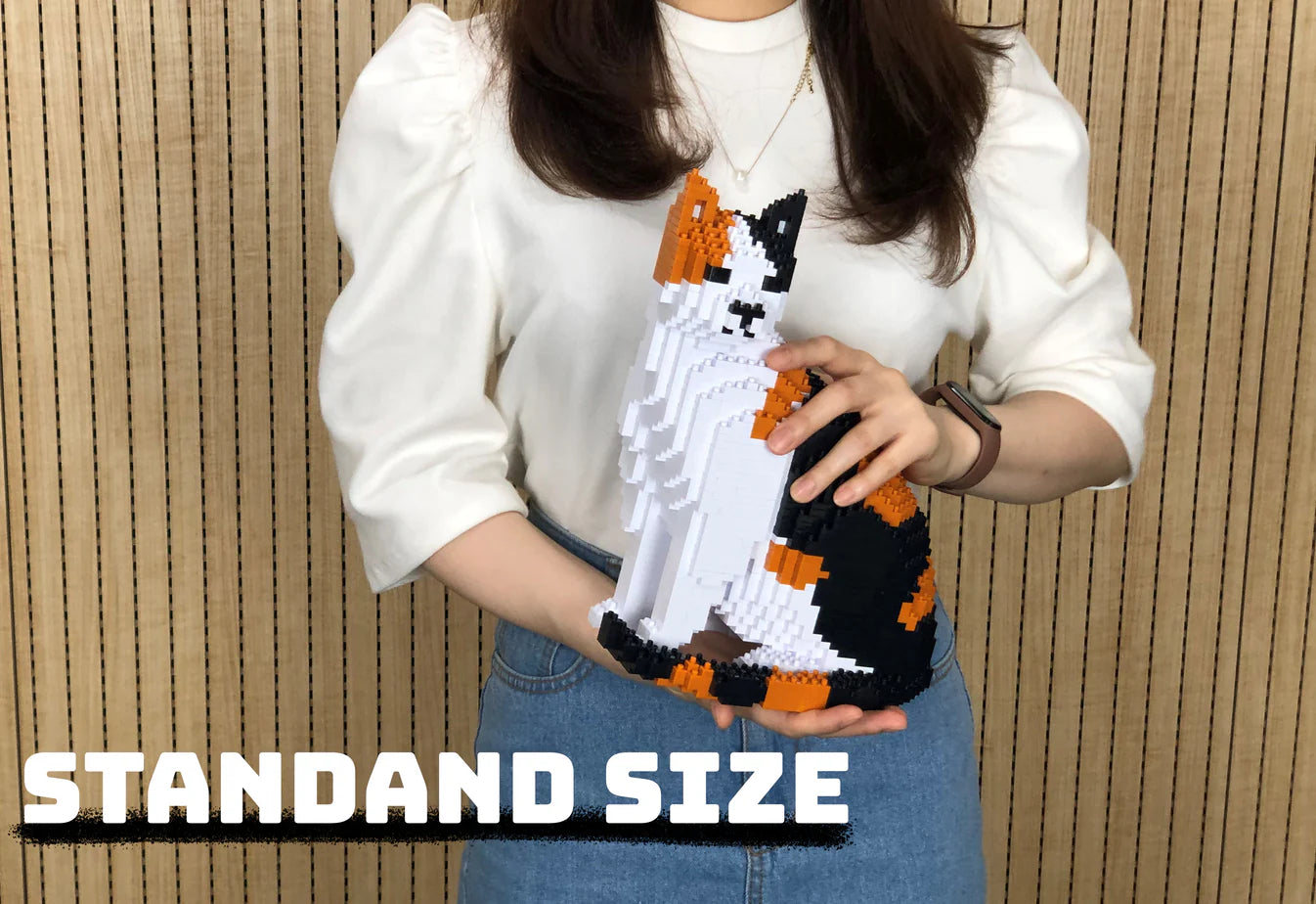 Person holding JEKCA Calico Cat building block model against a wooden panel background.